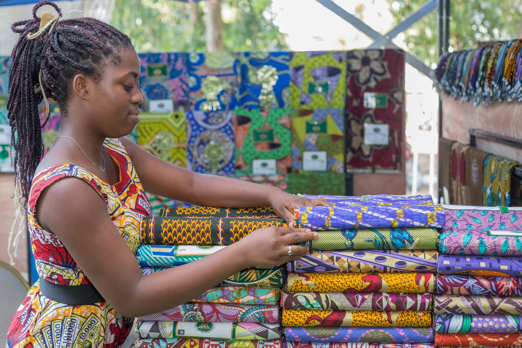 A trader arranging folded printed fabrics at a market stall