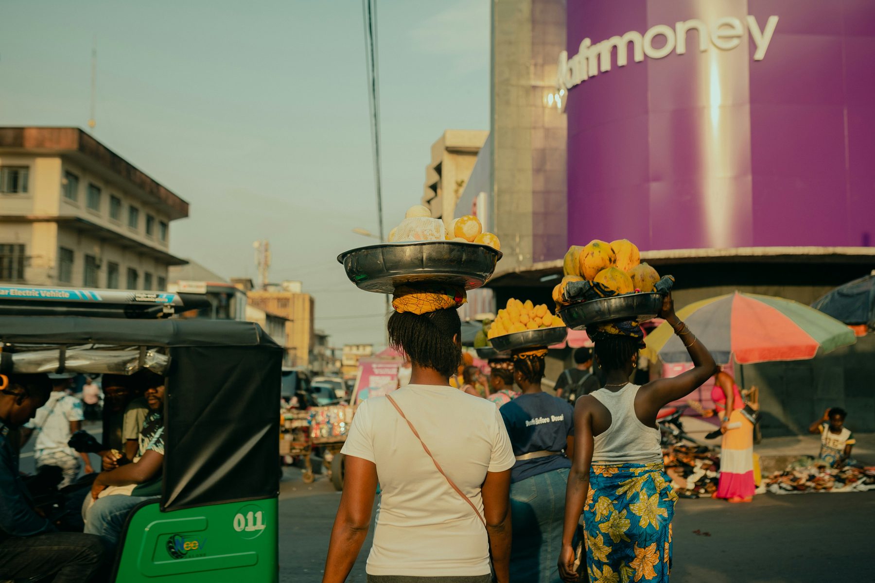 Traders carrying produce past a mobile money branch