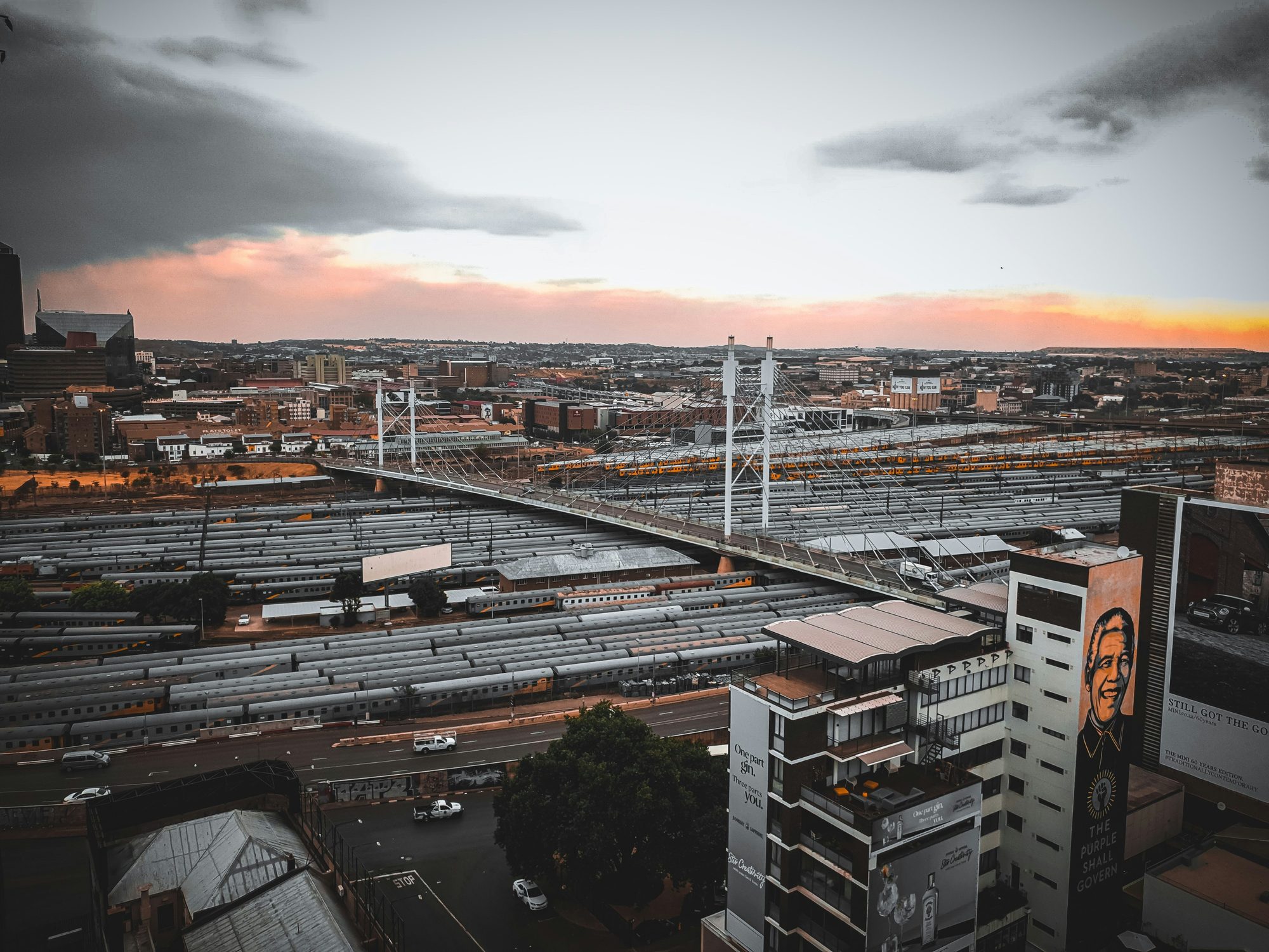 African city skyline at dusk with rail infrastructure and a suspension bridge